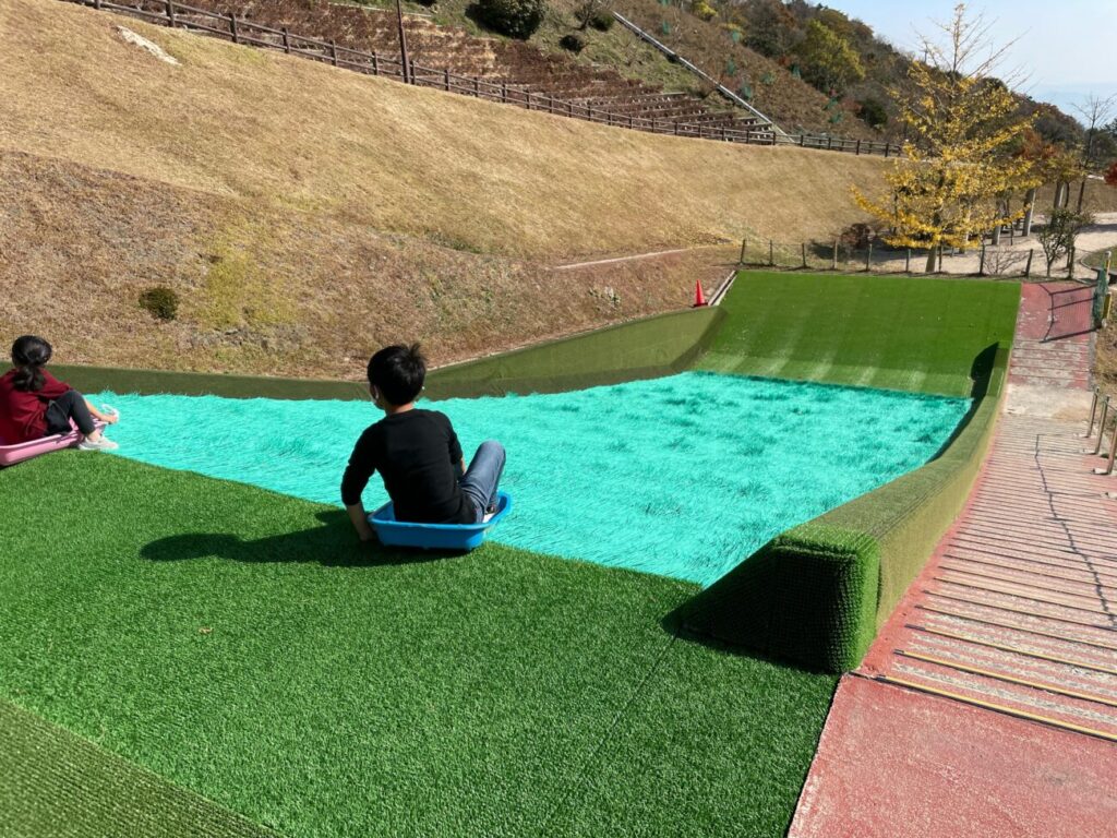 大平山山頂公園の芝滑りで遊ぶ２人の子供