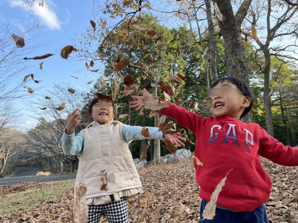 秋吉台家族旅行村で落ち葉を投げて遊ぶ子供